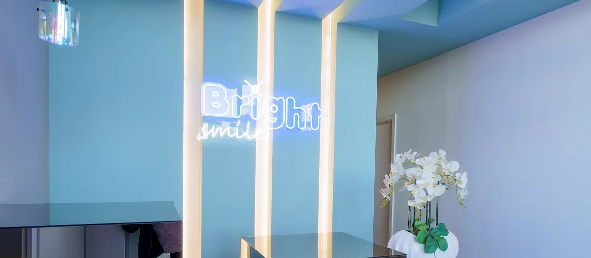 Receção da Bright Smile, com o néon da clínica na parede azul