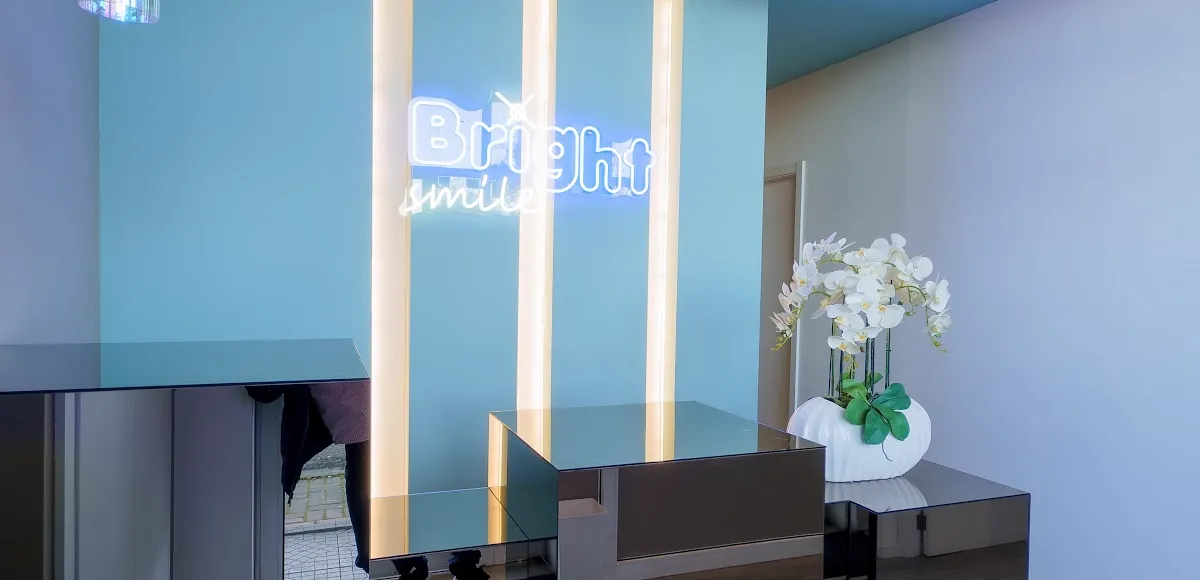 Receção da Bright Smile, com o néon da clínica na parede azul
